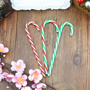 Close-up of three red, white, and green acrylic candy cane ornaments for Christmas tree decor