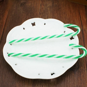 Close-up of green and white Christmas candy canes on a white ceramic lace plate