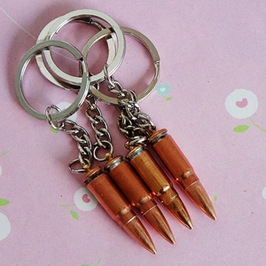 Set of four vintage brass bullet shaped metal keychains with silver chains and rings