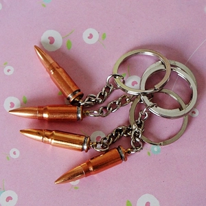 Detailed view of four metal bullet-shaped keychains with a vintage copper finish