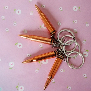 Detail view of four vintage bronze bullet shaped keychains on floral pattern background