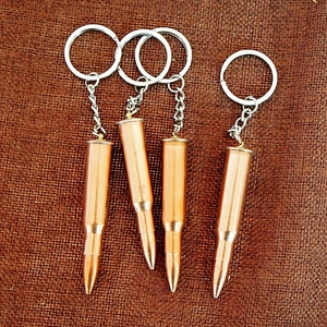 Detailed view of four brass-colored metal bullet-shaped keychains on a textured background