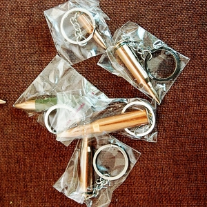 Macro shot of multiple brass bullet-shaped keychains in individual clear packaging bags