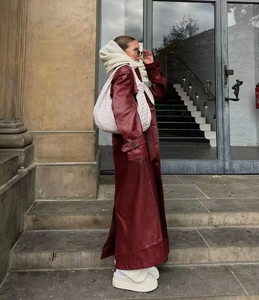 Gros plan d'un trench-coat en cuir rouge vin associé à un sac à main tissé rose chic