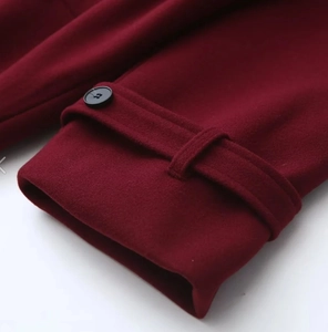 Detailed close-up of burgundy coat sleeve with buttoned cuff strap and wool texture