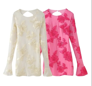 Détail de hauts en mesh avec broderie florale 3D et manches cloche élégantes en rose et crème