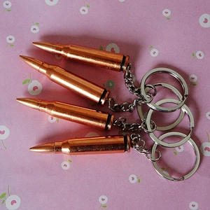 Detailed close-up of bullet-shaped metal keychains on a floral background