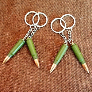 Detail of two AK-47 style bullet-shaped metal keychains on rustic brown burlap background