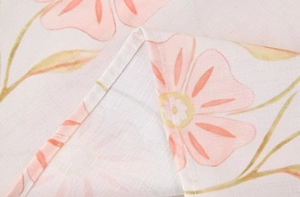 Détail d'imprimé floral rose sur tissu beige en coton-lin avec couture d'ourlet nette