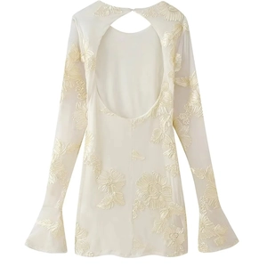 Détail de broderie et dos nu élégant sur la robe courte en dentelle florale couleur crème