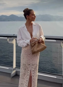 Close-up of knit crochet maxi skirt with side slit and straw clutch bag for vacation