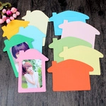 Close-up of colorful house-shaped paper photo frames displayed on a dark wood background