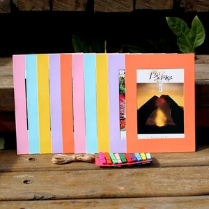 Detail of colorful DIY paper photo frames with mini wooden clips and jute rope on wood