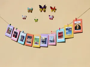 Colorful paper photo frames with small wooden clips and decorative 3D butterfly wall stickers