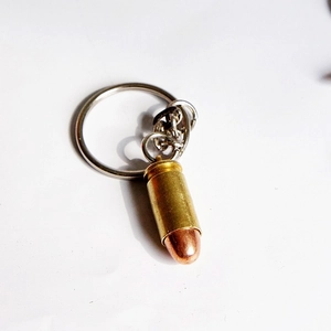 Close-up of a bullet-shaped metal keychain with brass finish and a polished copper tip