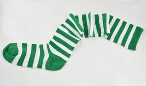Vue à plat de chaussettes hautes rayées vertes et blanches sur un fond blanc froissé