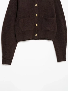 Detail view of dark brown knit cardigan with golden buttons and ribbed hem texture