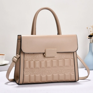 Elegant beige embossed crossbody bag with metallic clasp and adjustable strap in minimalist setting