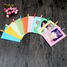 Detail of colorful paper photo frames with mini wooden clips on a dark wood background