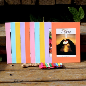 Colorful paper photo frames set with clips and hemp rope on a wooden background