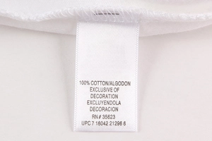 Détail de l'étiquette d'entretien indiquant 100% coton et finitions des coutures
