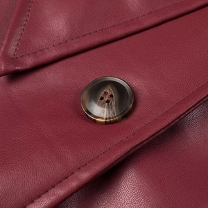 Detail of dark red faux leather texture with neat stitching and marble pattern button