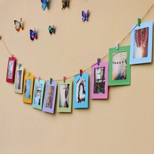 Close-up of colorful paper photo frames with mini wooden clips and twine for wall decor