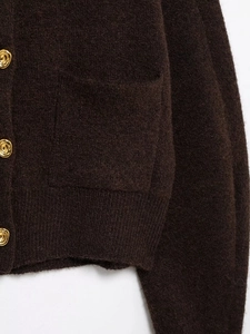 Detail of dark brown knit cardigan with soft mohair texture and golden embossed buttons