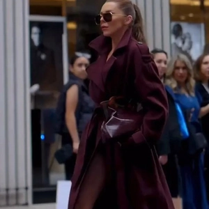 Detail of burgundy long coat featuring wide lapels and a waist belt in street style