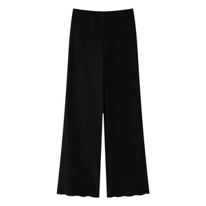 Dettaglio dei pantaloni neri a gamba larga con trama a pieghe verticali e vita alta elastica