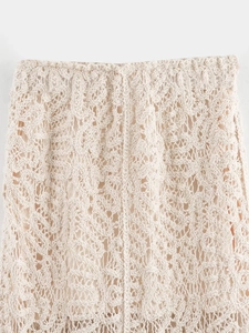Close-up detail of beige crochet knit skirt featuring intricate hollow out patterns