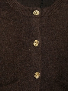 Close-up of dark brown knit cardigan texture and decorative golden metal buttons