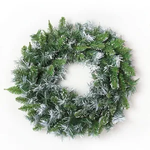 Classic green artificial pine Christmas wreath with snowy white flocking on white background