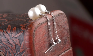 Close-up of elegant long tassel earrings with white pearls and polished silver chains