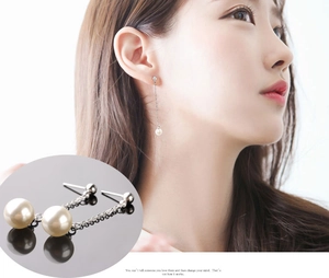 Detailed macro view of long silver tassel earrings with white pearls and sleek metal chains