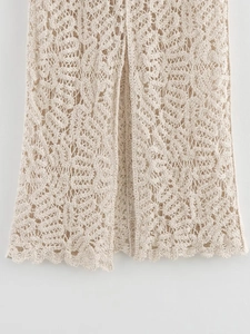 Detailed close-up of intricate scalloped hem and hollow crochet knit pattern on beige dress