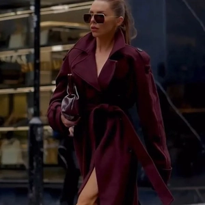 Detail of dark wine red long coat featuring a broad lapel and matching waist belt buckle