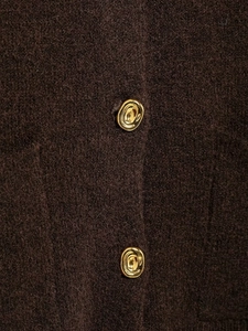 Detailed macro view of high-quality brown knitted fabric with textured gold lava buttons
