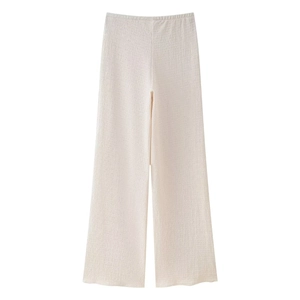 Dettaglio macro dei pantaloni plissé crema che mostra la trama fine e la vita alta elastica