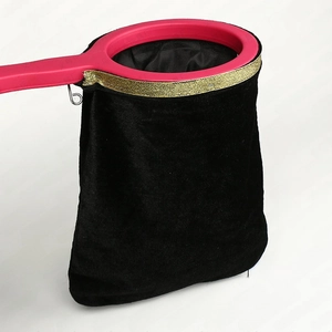 Macro detail of magic velvet changing bag with gold trim and red circular handle