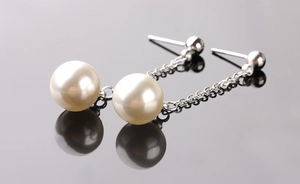 Detailed macro view of long tassel silver earrings with premium round cream pearls