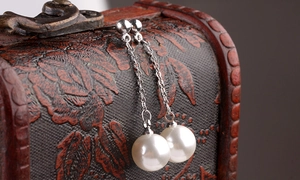Detailed macro view of white pearl drop earrings hanging on a vintage wooden jewelry box