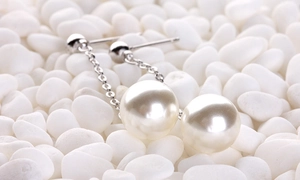 Macro shot of long silver tassel earrings with round pearls on white smooth pebbles