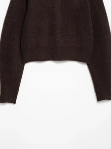 Detail of dark brown knit sweater with thick texture and ribbed hem and cuffs