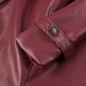 Macro detail of wine red leather sleeve cuff with matching button and stitching