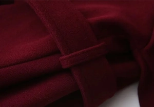 Detailed view of the burgundy wool coat waist belt loop and precise stitching texture