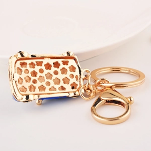 Gold beetle car keychain with blue enamel detail and floral pattern on back view
