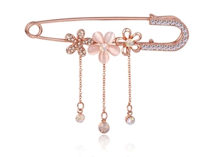 Detail of rose gold bow brooch featuring cat-eye stone, rhinestones, and hanging tassels