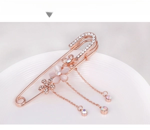 Detail of rose gold flower brooch with pink cat eye stone and dangling tassel chains