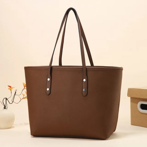 Close-up of dark brown pebble leather tote bag with silver rivets and slim shoulder straps